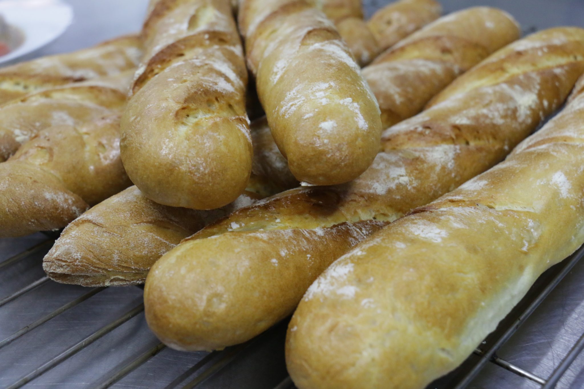 Baguettes dusted with flour on a cooling rack, by Jackson Monichan