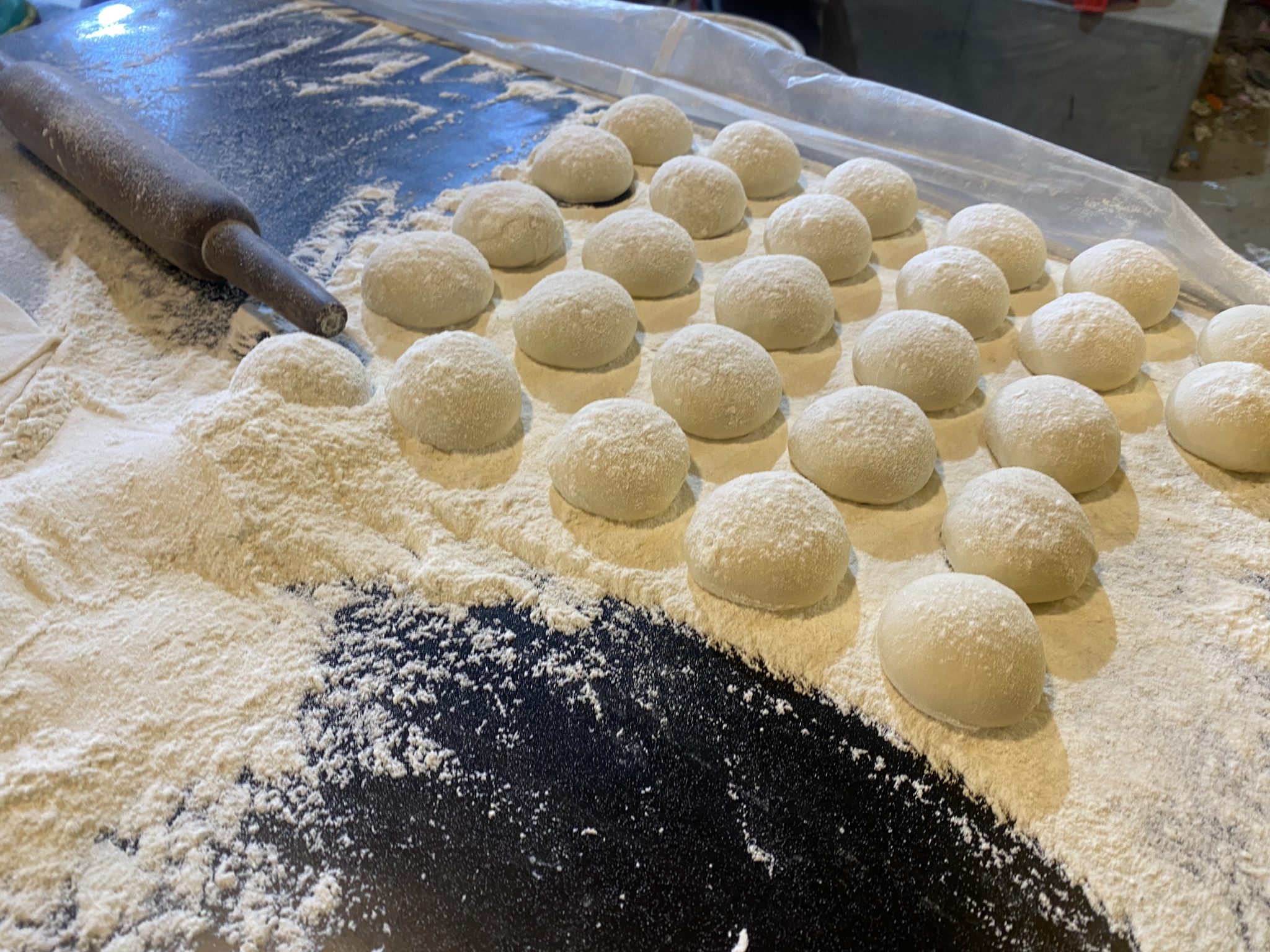 Round dough balls covered in flour, set out in rows, by Tawhid Sadman